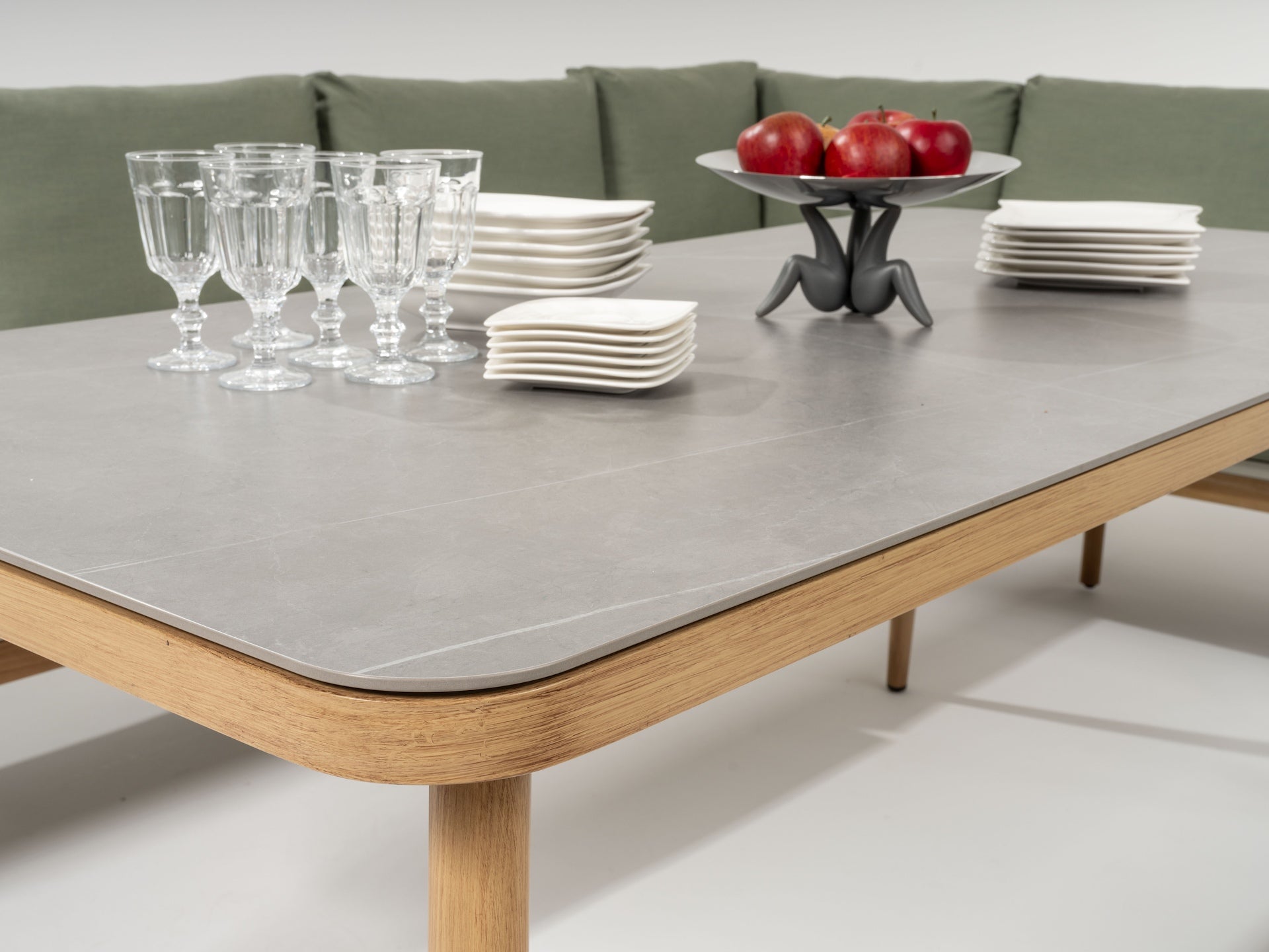 Alicia Garten Eckbankgruppe mit grauer Sinterstein-Tischplatte und grünen Kissen auf robustem Aluminiumgestell in Holzoptik.