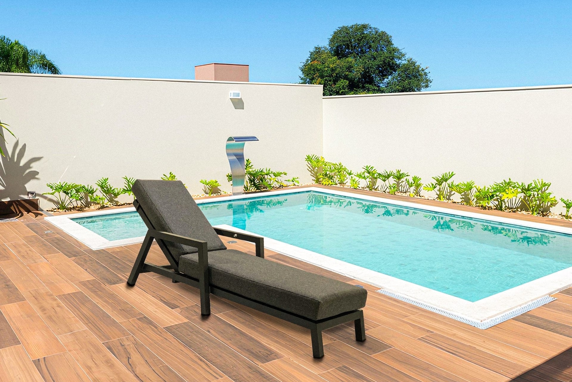 Moderne Sonnenliege Bibi mit anthrazitfarbenem Aluminiumgestell und dunkelgrauer Kissenauflage, verstellbar für ultimativen Komfort an einem sonnigen Poolbereich.