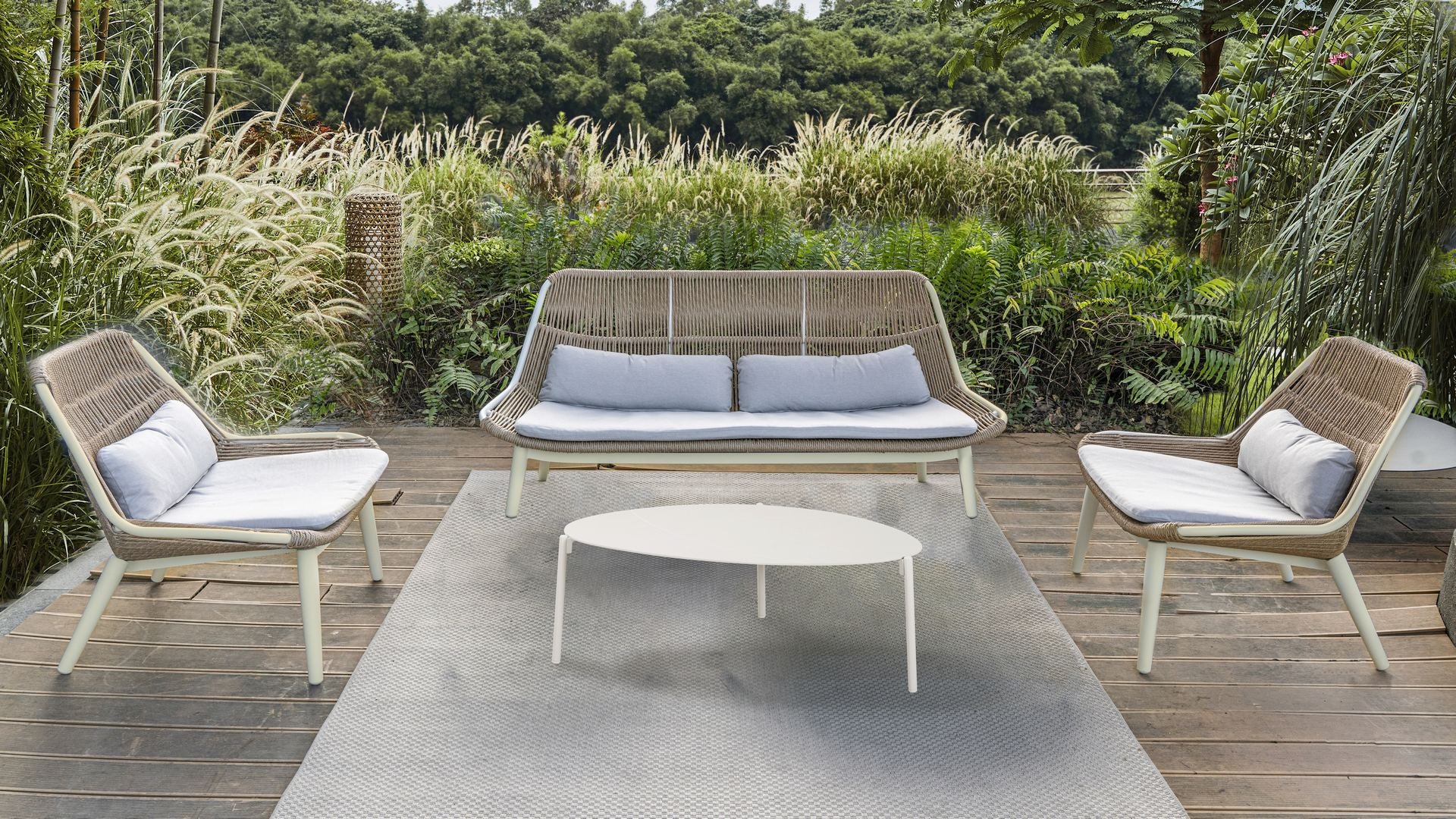 Loungeelemente Celeste mit ivoryfarbenem Aluminiumgestell, sandfarbenen Textilschnüren und hellgrauen Polstern. Ovaler und runder Couchtisch aus Aluminium.